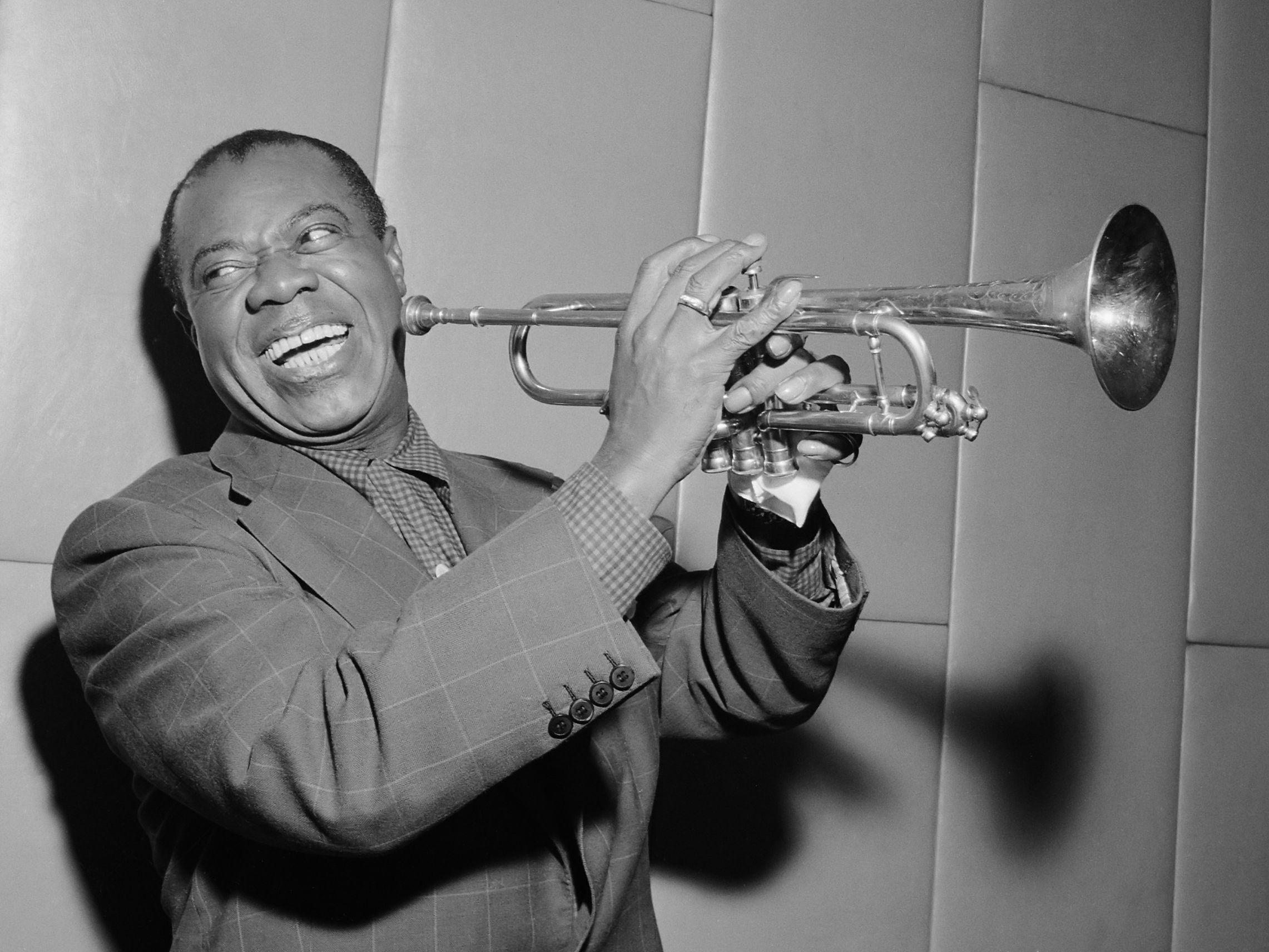 Louis laughing and playing his trumpet in 1955