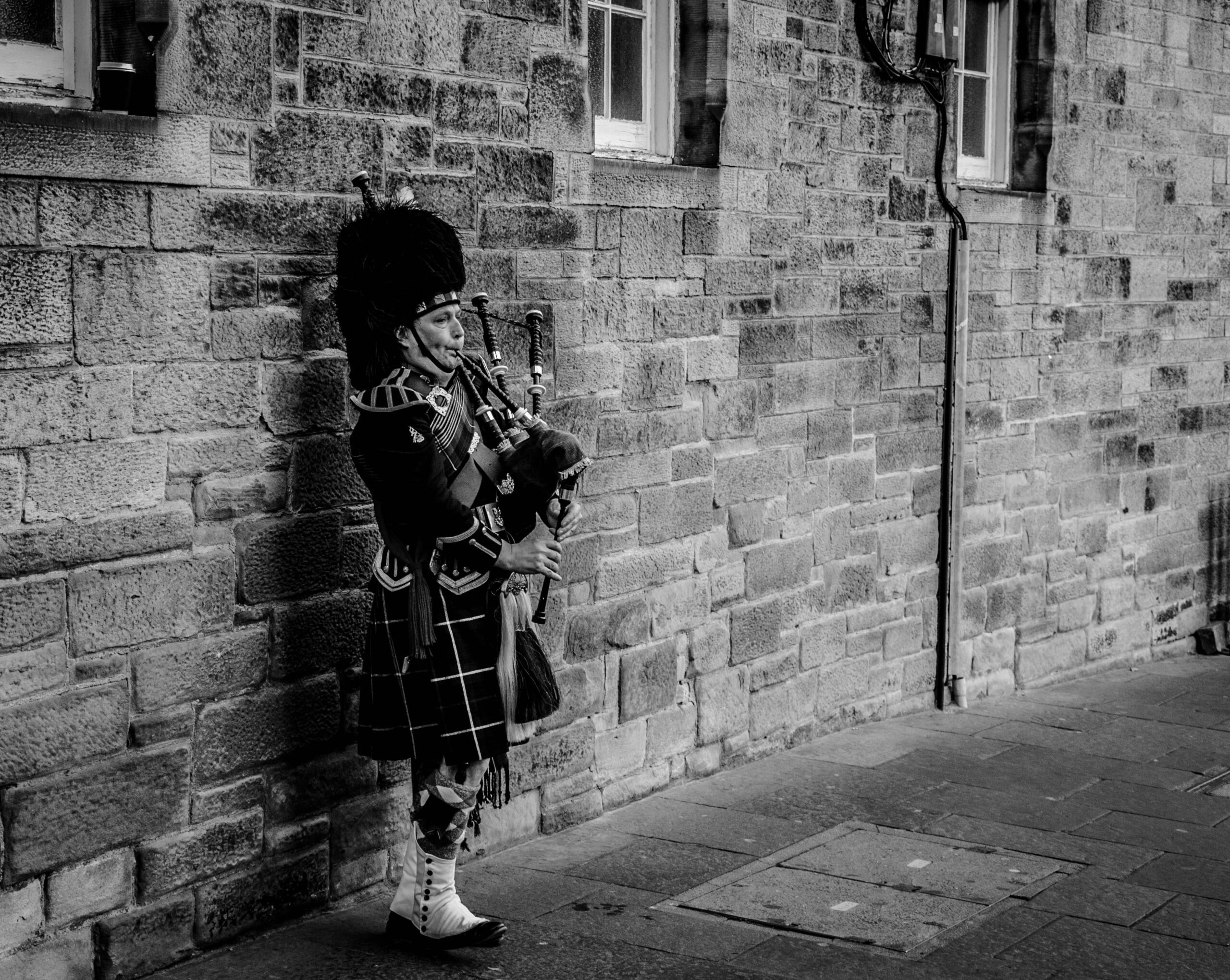 Person Using Bagpipes Near Wall in Grayscale Photography · Free